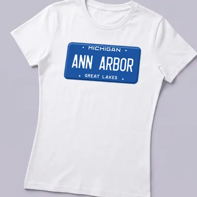Vintage-style t-shirt featuring a Michigan license plate graphic in blue and white — printed on a women's shirt