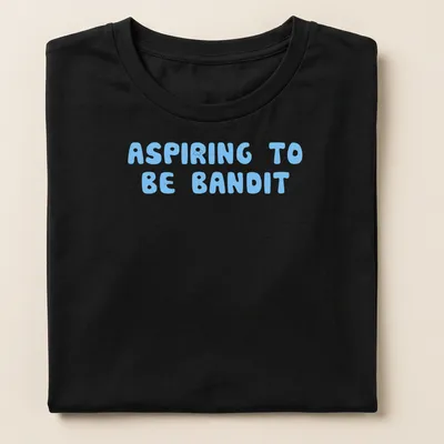 Playful bubble letters spelling ASPIRING TO BE BANDIT on light blue background — printed on a women's shirt