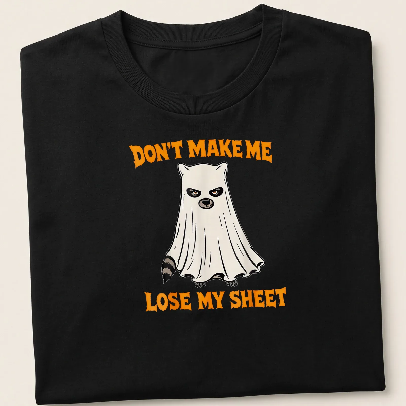 Cartoon ghost raccoon with humorous text about losing a sheet in orange, black, and white — printed on a unisex t-shirt