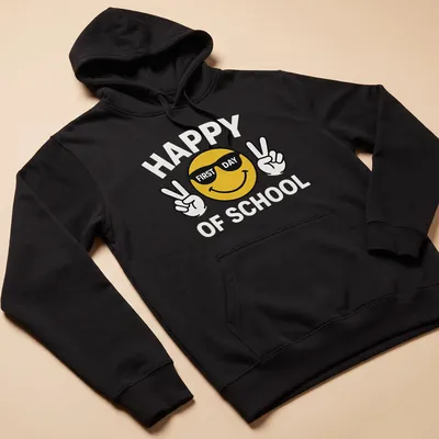 Playful cartoon smiley face with the text 'Happy First Day Of School' in yellow and black — printed on a unisex hoodie