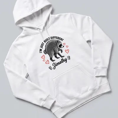 Illustrative t-shirt featuring raccoon and text 'I'm Just Built Different Jimothy' in black, white, and red. — printed on a unisex hoodie