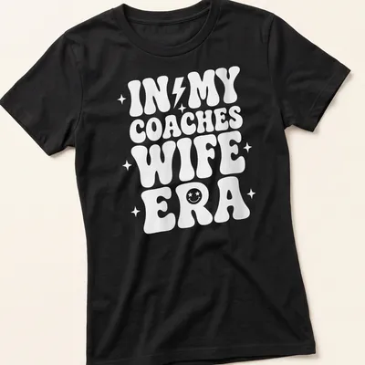 Bold typography t-shirt with IN MY COACHES WIFE ERA text in white — printed on a women's shirt