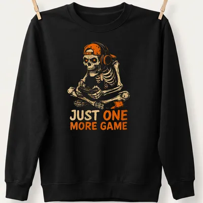 Cartoon skeleton playing video games with the text 'JUST ONE MORE GAME' in fun lettering. — printed on a unisex sweatshirt
