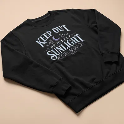Vintage dark humor t-shirt featuring a moon and floral elements with the text 'KEEP OUT OF DIRECT SUNLIGHT' — printed on a unisex sweatshirt
