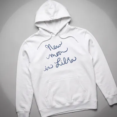 Handwritten script of 'New moon in Libra' on a navy blue — printed on a unisex hoodie