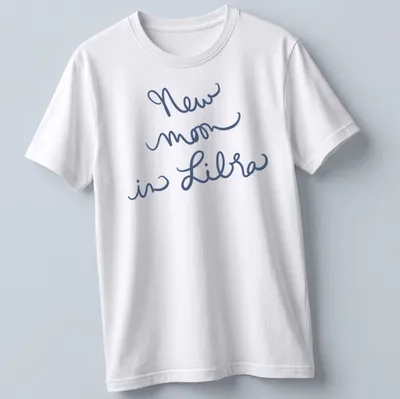 Handwritten script of 'New moon in Libra' on a navy blue t-shirt